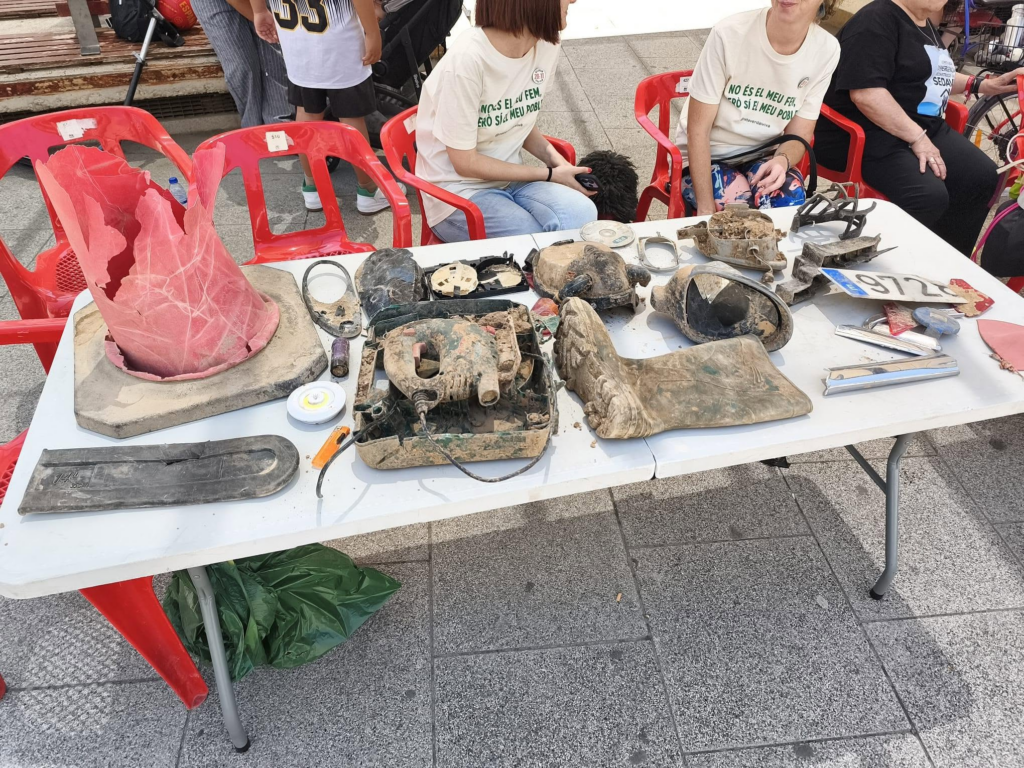 Taula del que hem anomenat "museu dels horrors", tota mena d'objectes (parts de cotxes, ensers doméstics) que clarament porten enterrats des de la DANA i que per fi surten del nostre sol.
